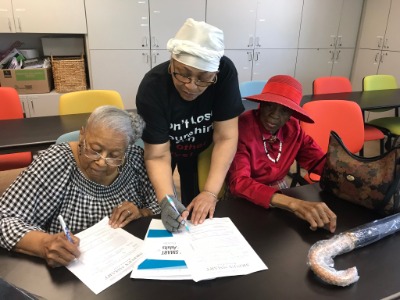 Three elderly ladies completing a form