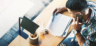 Man on phone while reading newspaper